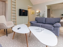 Uma sala de estar moderna com um sofá cinzento, uma mesa de centro branca e um tapete estampado.