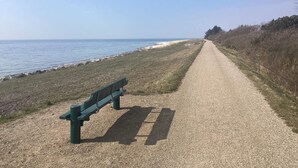 A gravel path beside a body of water with a bench and a fence on one side. - 6 Person Holiday Home in Dannemare (Dannemare)