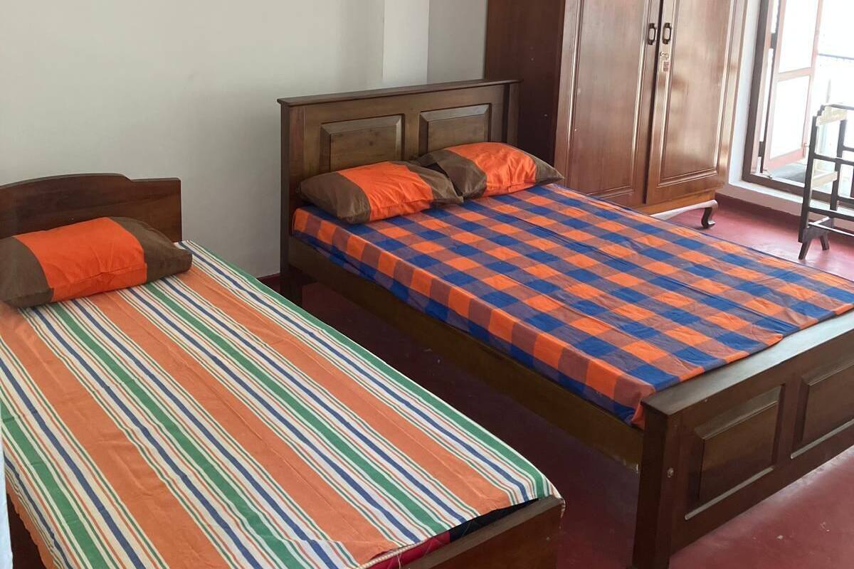 A bedroom with two beds, a wardrobe, and a window.