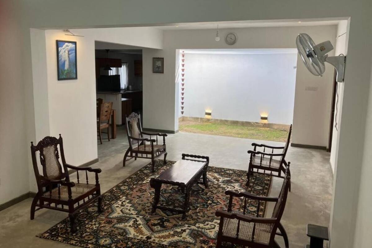 A living room with a patterned rug, wooden furniture, and a view of a garden.