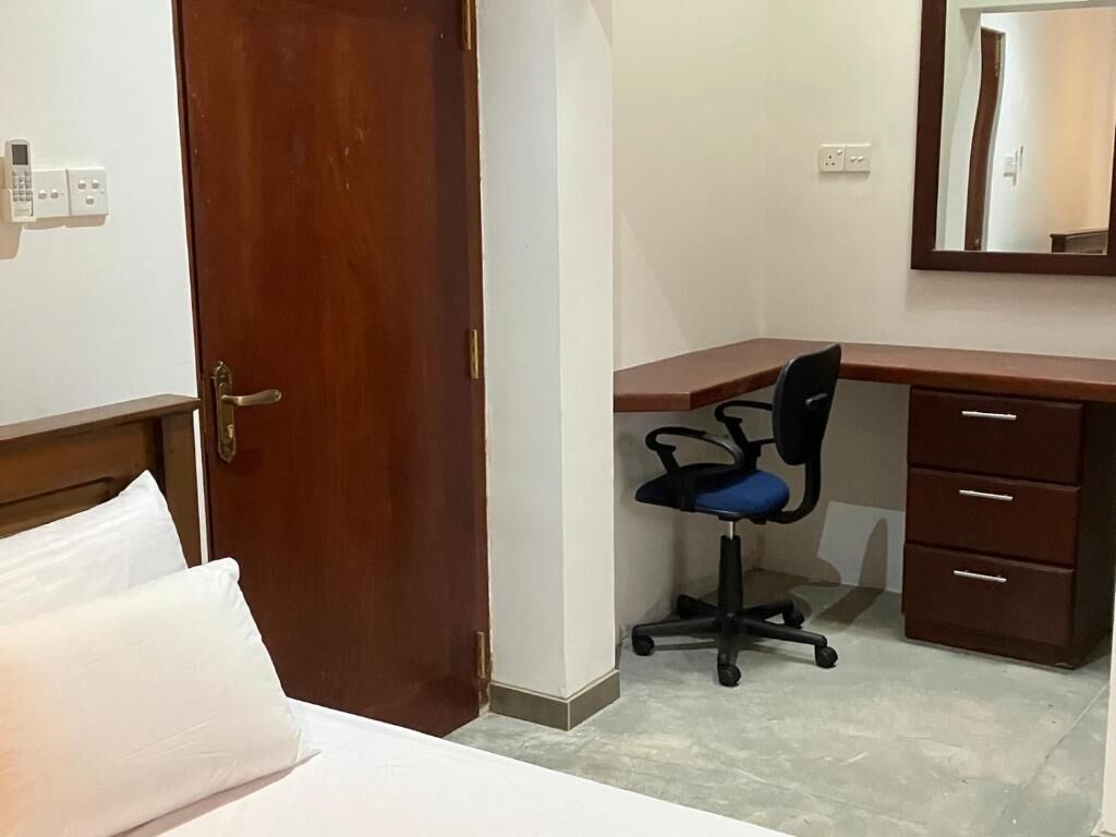 Una habitación de hotel con cama, escritorio, silla, cómoda y espejo.