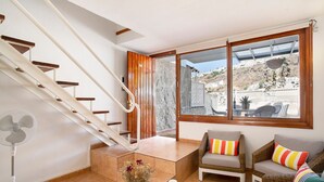A staircase leading to a balcony with a view of a hillside, wicker furniture, a fan, and a vase with flowers. - Vacation Apartment 'Dúplex Guayana 23 En Puerto Rico' with Mountain View, Shared Pool and Wi-Fi (Mogán)