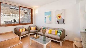 A living room with a sofa, two armchairs, a coffee table, and a view of a mountainous landscape through large windows. - Vacation Apartment 'Dúplex Guayana 23 En Puerto Rico' with Mountain View, Shared Pool and Wi-Fi (Mogán)