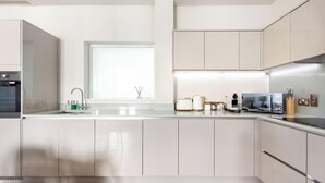A modern kitchen with white cabinets, a built-in oven, a sink, and various appliances. - 5 Mins Walk to Battersea Park Battersea Retreat (London)