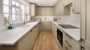Una cocina moderna con armarios blancos, piso de madera y ventana que proporciona luz natural.