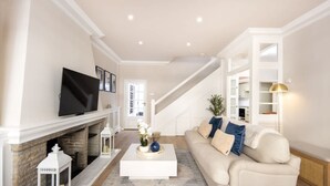 Una sala de estar con chimenea, televisión, escalera y sofá.
