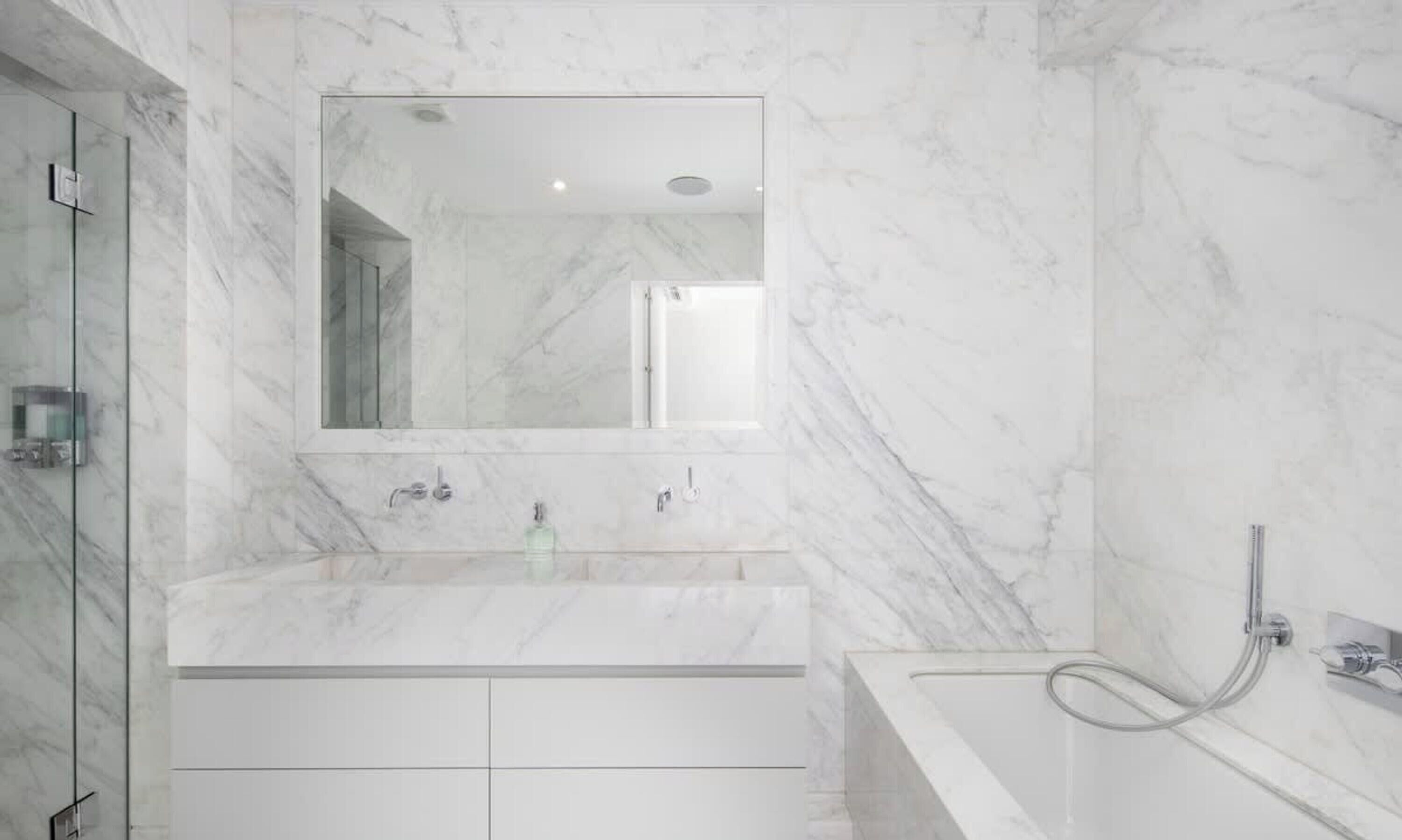 Un bagno moderno con un lavabo in marmo, uno specchio grande e una zona doccia.