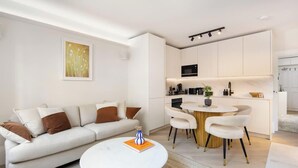 Una sala de estar moderna con sofá, mesa de centro y comedor con sillas y una pequeña mesa.