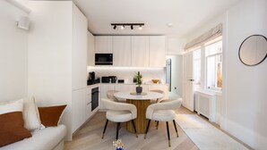 Una cocina moderna con armarios blancos, una isla central con sillas, un microondas y una cafetera.