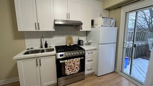 Uma cozinha compacta com armários brancos, fogão de aço inoxidável, micro-ondas e geladeira.