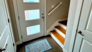 Un couloir avec une porte blanche, un tapis bleu et un escalier en bois.