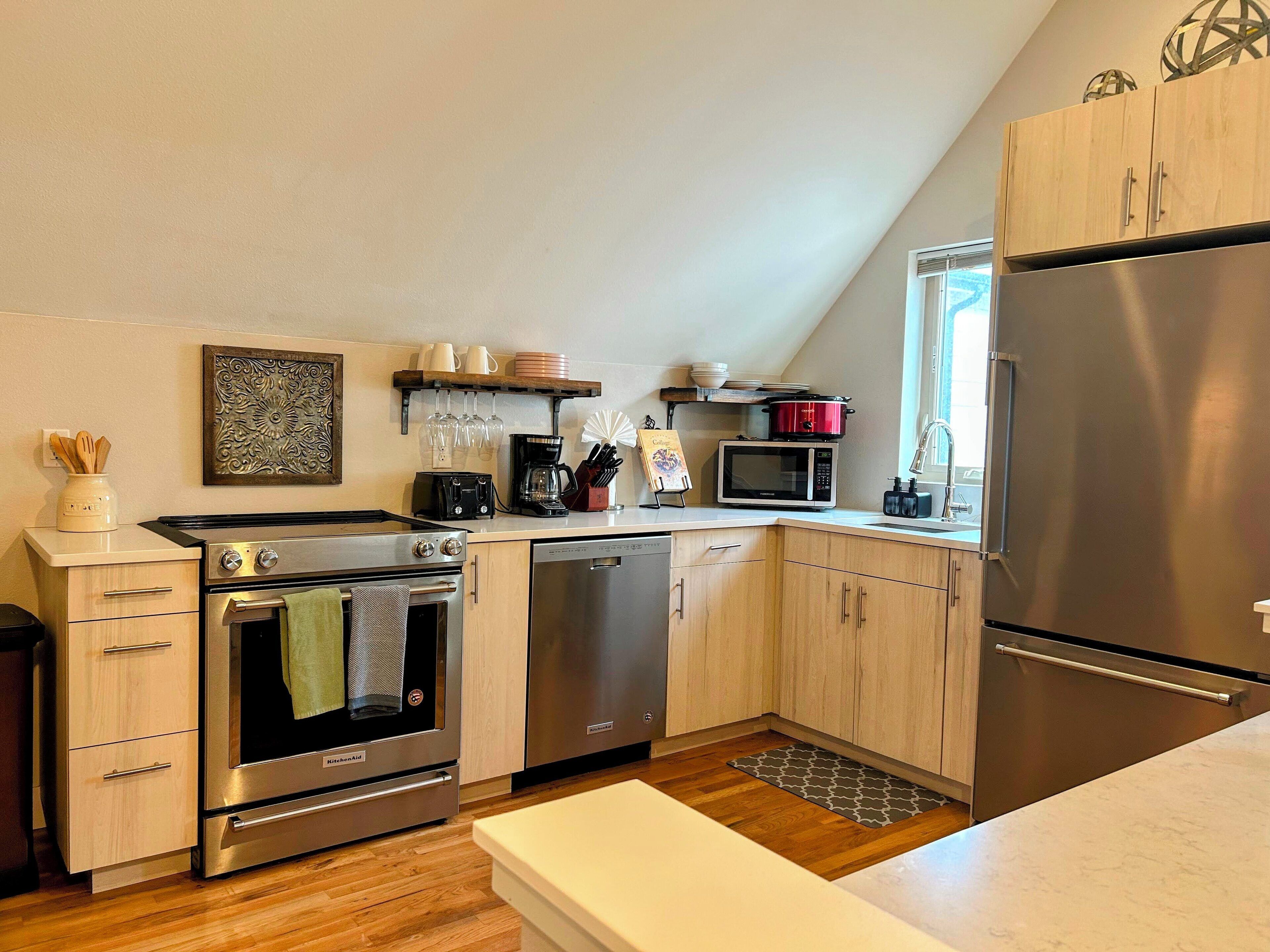 Une cuisine moderne dotée d’appareils électroménagers en acier inoxydable, de meubles en bois et d’un petit îlot central.