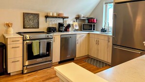Une cuisine moderne dotée d’appareils électroménagers en acier inoxydable, de meubles en bois et d’un petit îlot central.
