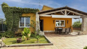 Una casa con porche cubierto, comedor y jardín.