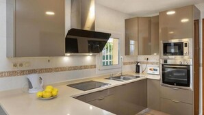 Una cocina moderna con una isla grande, horno empotrado, microondas y ventana.