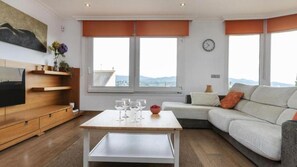 Un salon moderne avec un canapé, une table basse sur laquelle sont posés des verres, un téléviseur et un tableau accroché au mur.