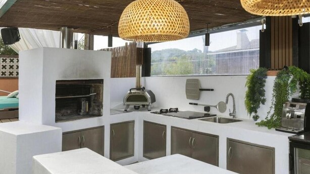 Una cocina al aire libre con una parrilla, un lavamanos y armarios.