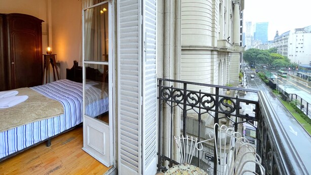 Une chambre à coucher avec un lit, une table de chevet et une fenêtre avec des rideaux.