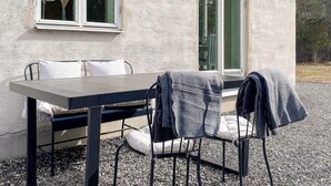Um pátio com uma mesa, cadeiras, uma janela e uma porta.