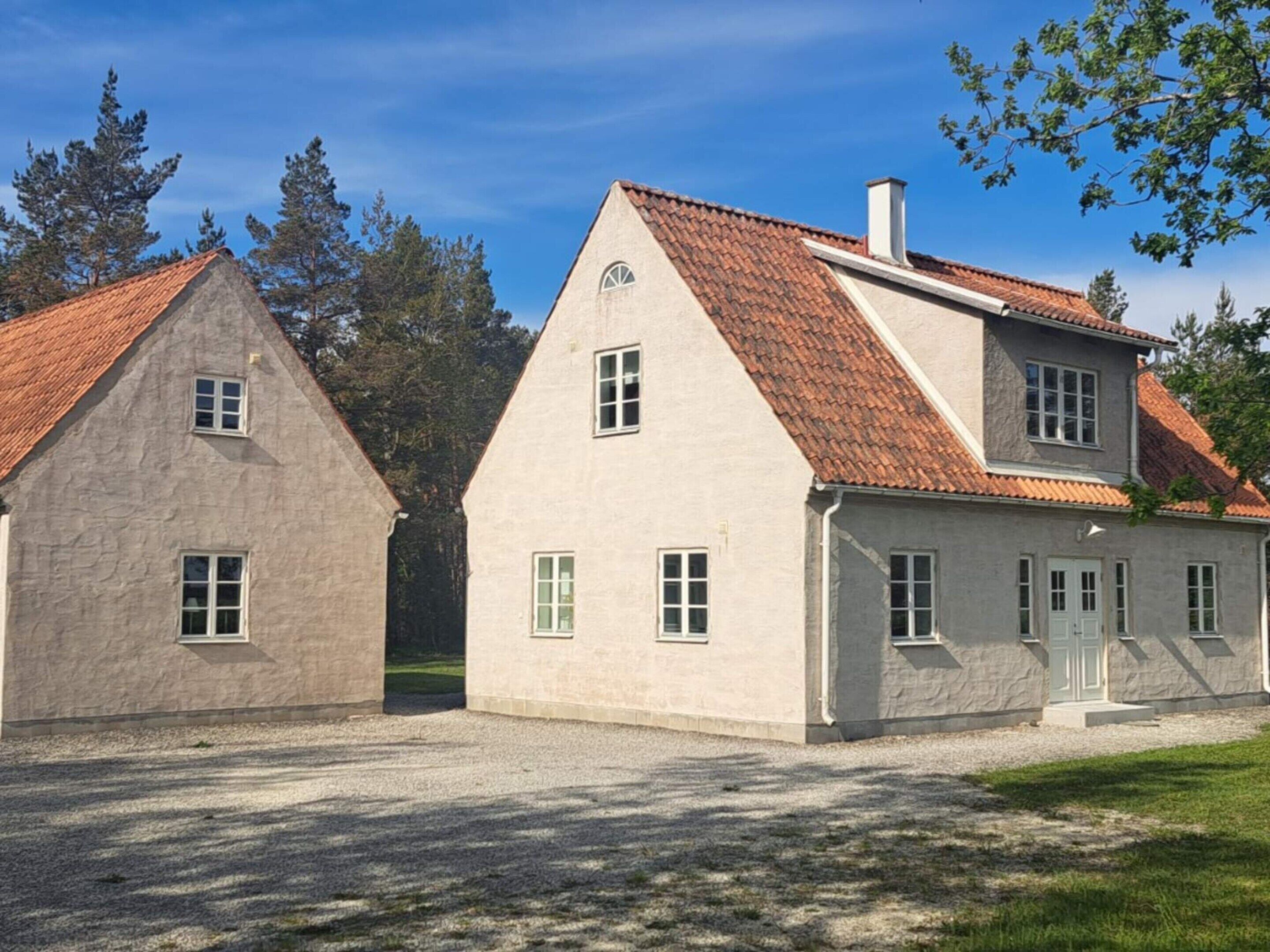 Un bâtiment à deux étages, avec un toit recouvert de tuiles rouges, une façade en pierre et un petit porche.
