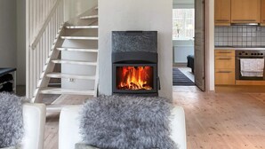 Um interior moderno com lareira, escada de madeira e área de cozinha.