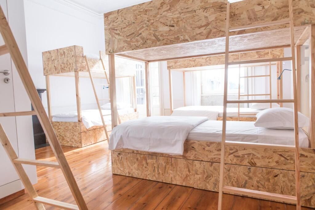 A room with a bunk bed made of wood, a ladder, and a wooden wardrobe.