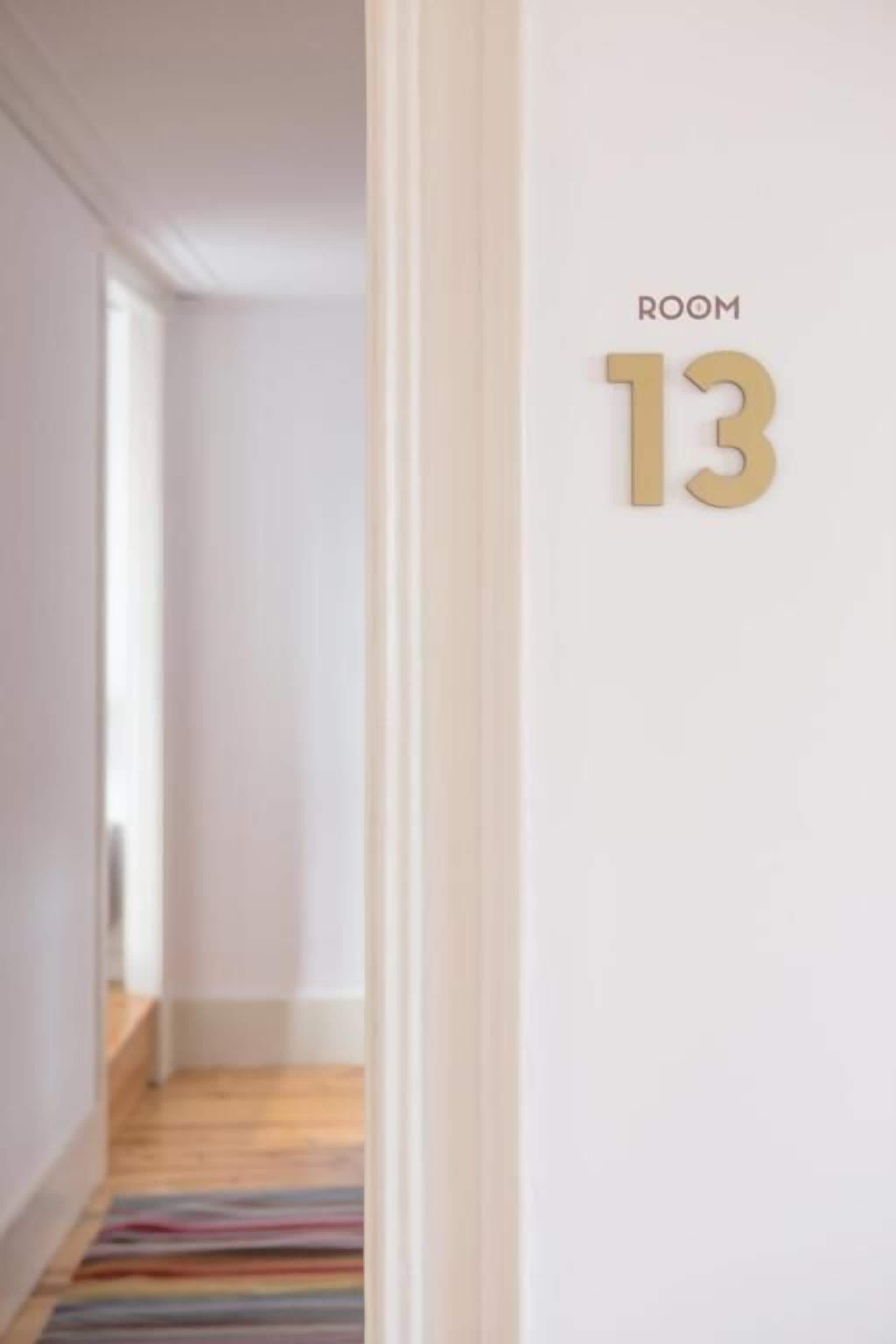 A hallway with a striped rug leading to a door labeled "ROOM 13".