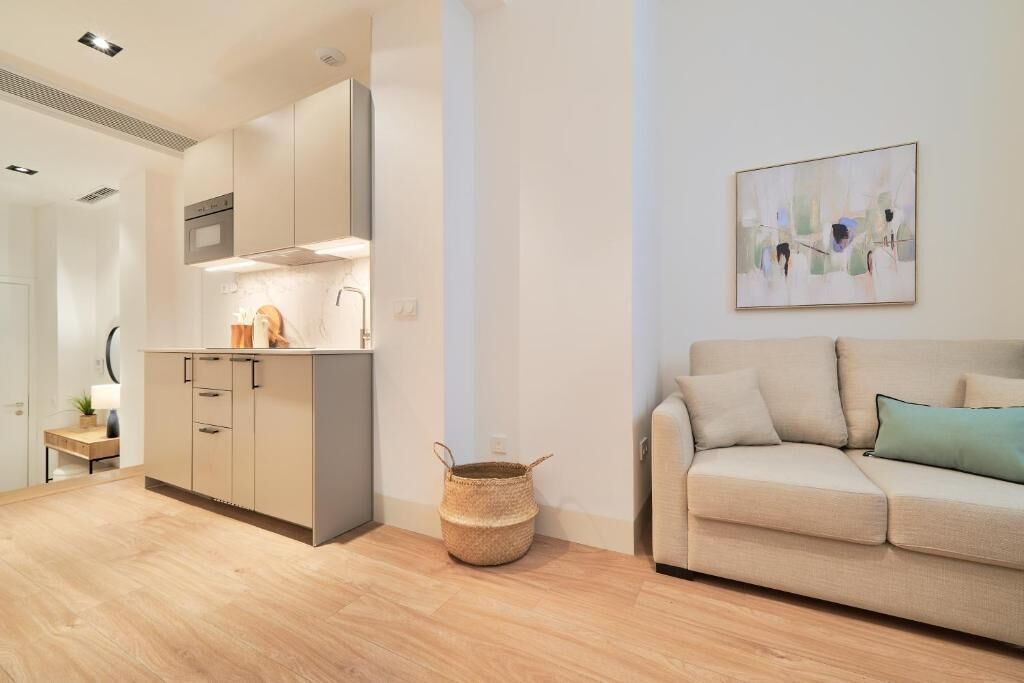 A modern apartment with a kitchen, a sofa, and a painting on the wall.