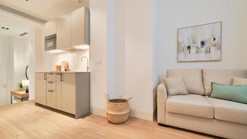 A modern apartment with a kitchen, a sofa, and a painting on the wall.