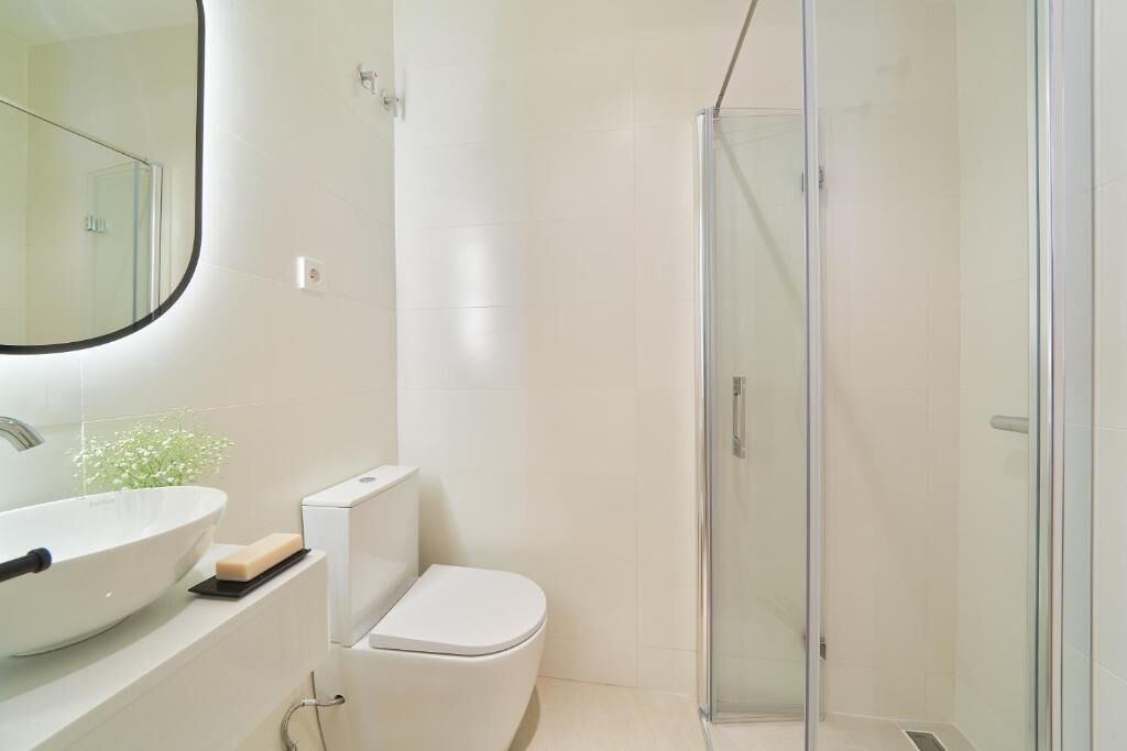 Un bagno moderno con un lavandino capiente, il water e uno spazio doccia con pareti in vetro.
