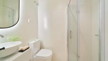 Ein modernes Badezimmer mit einem großen Waschbecken, einer Toilette und einer Duschkabine aus Glas.