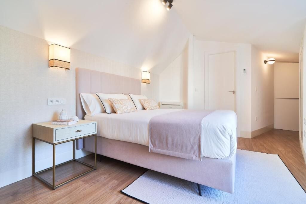 A bedroom with a bed, bedside table, and two wall-mounted light fixtures.