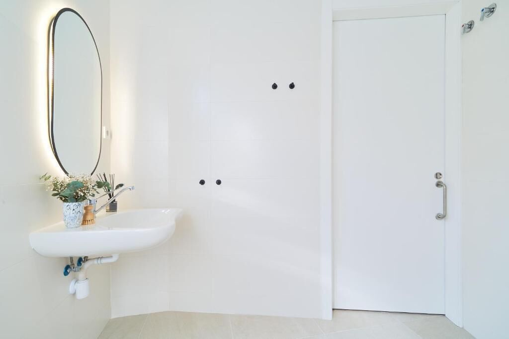 A bathroom with a white sink, a mirror, and a door.