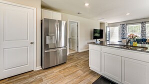 A modern kitchen with white cabinetry, stainless steel appliances, and a granite countertop. - Ocean Breeze Escape! (Ocean Isle Beach)