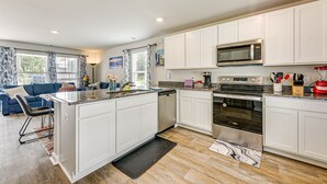 A modern kitchen with white cabinetry, stainless steel appliances, and a central island. - Ocean Breeze Escape! (Ocean Isle Beach)