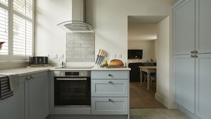 Una cocina moderna con horno empotrado, tabla de cortar y ventana con persianas.