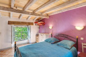 Une chambre à coucher avec un lit, une fenêtre, une commode et une chaise.