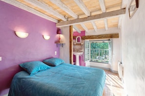 Un dormitorio con cama, ventana, lavamanos y vistas a zonas verdes.