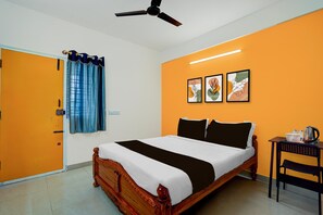 A hotel room with a bed, a ceiling fan, a window with curtains, and artwork on the wall. - Family Room Tachoma House (Bengaluru)