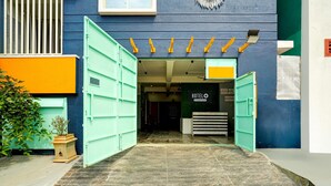 A hotel entrance with a green door, a sign reading 'HOTEL', and a tiled floor.
