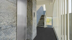 A hallway with a door, a staircase, and a railing.