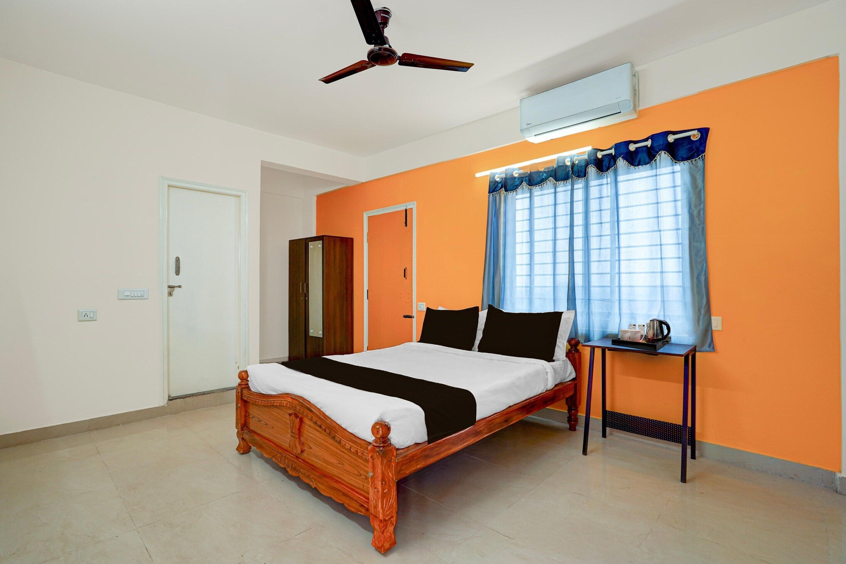 Un dormitorio con cama de madera, aire acondicionado, ventilador de techo y ventana con cortinas.