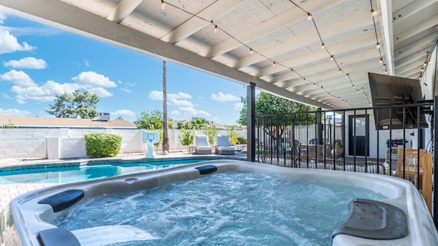 Ein Whirlpool mit Blick auf ein Schwimmbecken und eine Außenlounge.