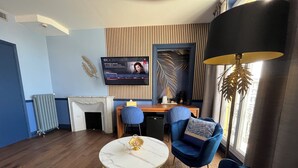Un salon moderne avec une cheminée, une table ronde, des chaises bleues et un téléviseur fixé au mur.