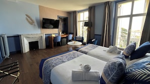 Une chambre d’hôtel avec deux lits, un bureau, une chaise, une télévision et une cheminée.