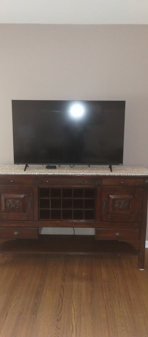 A wooden TV stand with a flat-screen TV on top. - Beautiful East Side Ranch (Wichita)