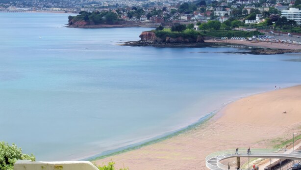 A coastal view with a beach, a cliff, and a town in the background. - The Renoir Sea View Suite (Torquay)