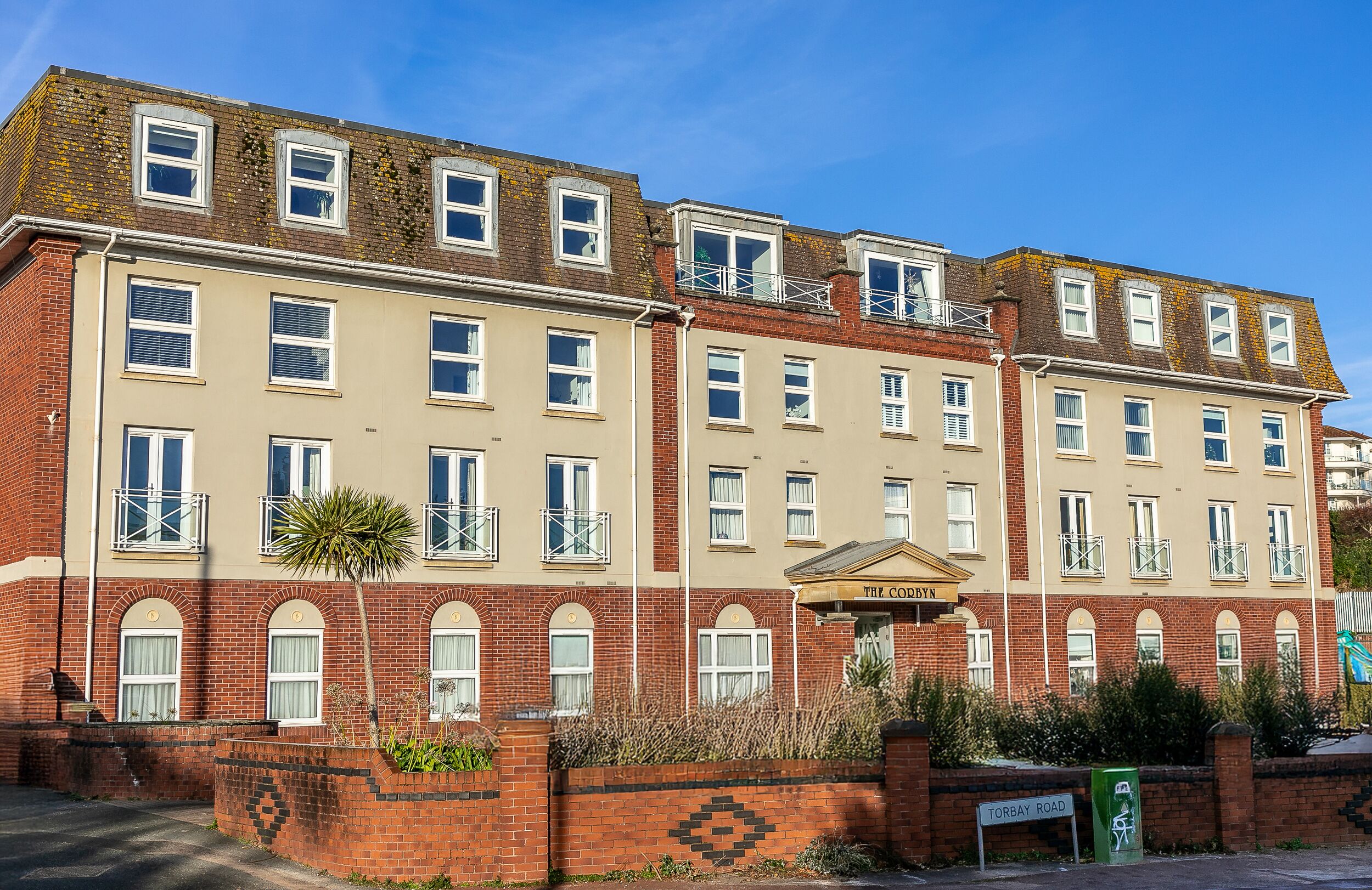 A multi-story building with a beige facade, red brick accents, and multiple balconies.