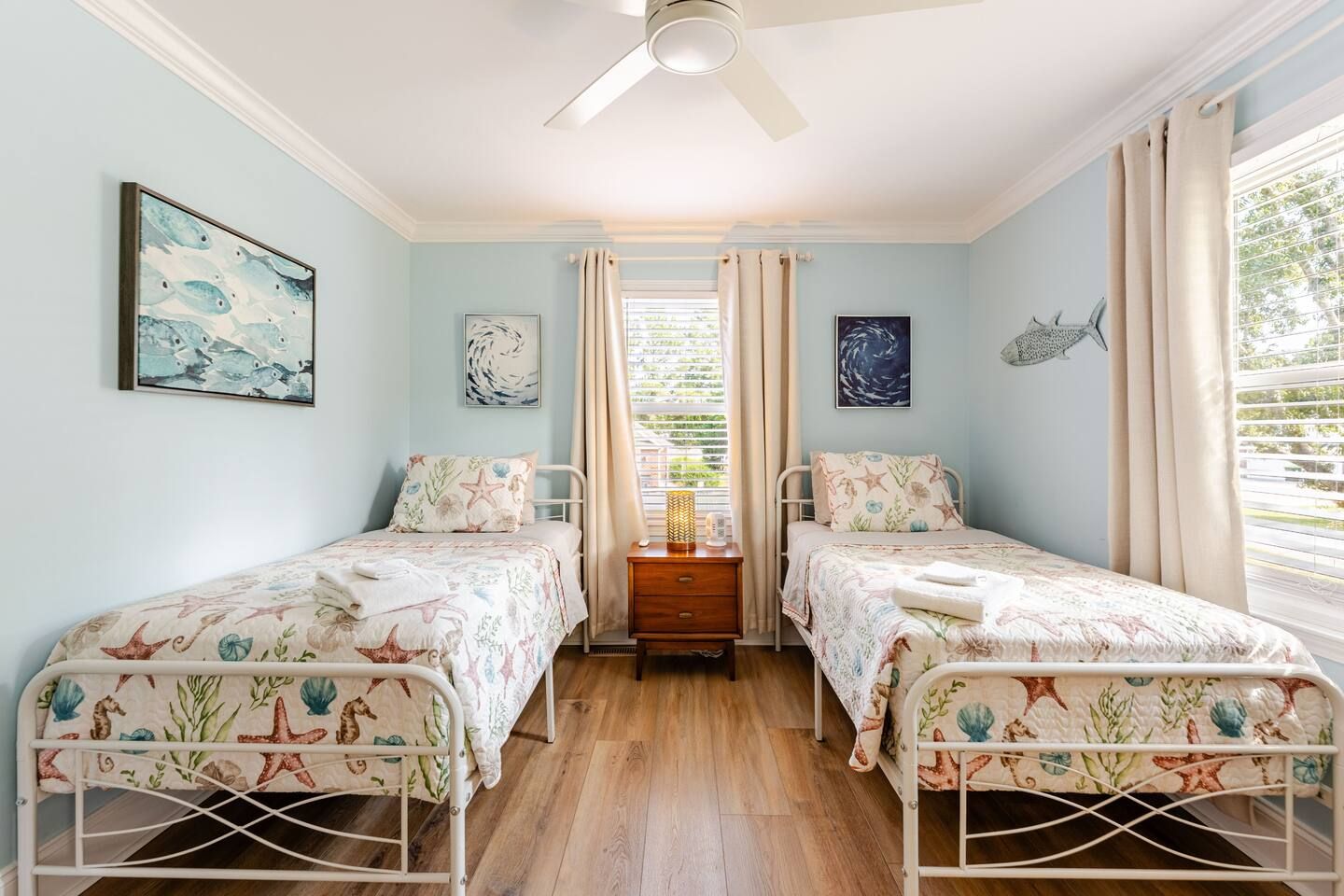 Ein Schlafzimmer mit zwei Betten, einem Deckenventilator und Kunstwerken an den Wänden.