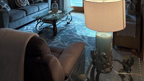 Ein Wohnzimmer mit Holzbalkendecke, einem Sofa, einem Couchtisch, einer Lampe und einem Fernseher.